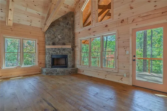 a view of an empty room with wooden floor and a fireplace
