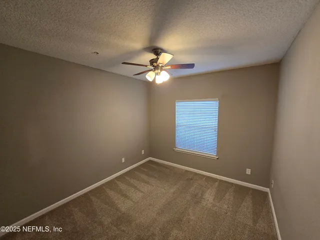 a view of swimming pool with seating space and trees in the background