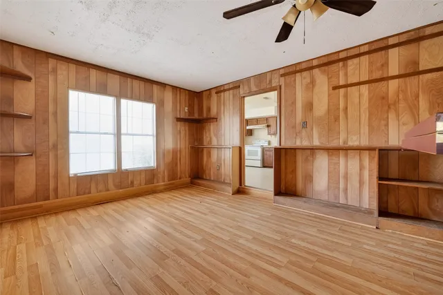 a view of empty room with wooden floor and fan