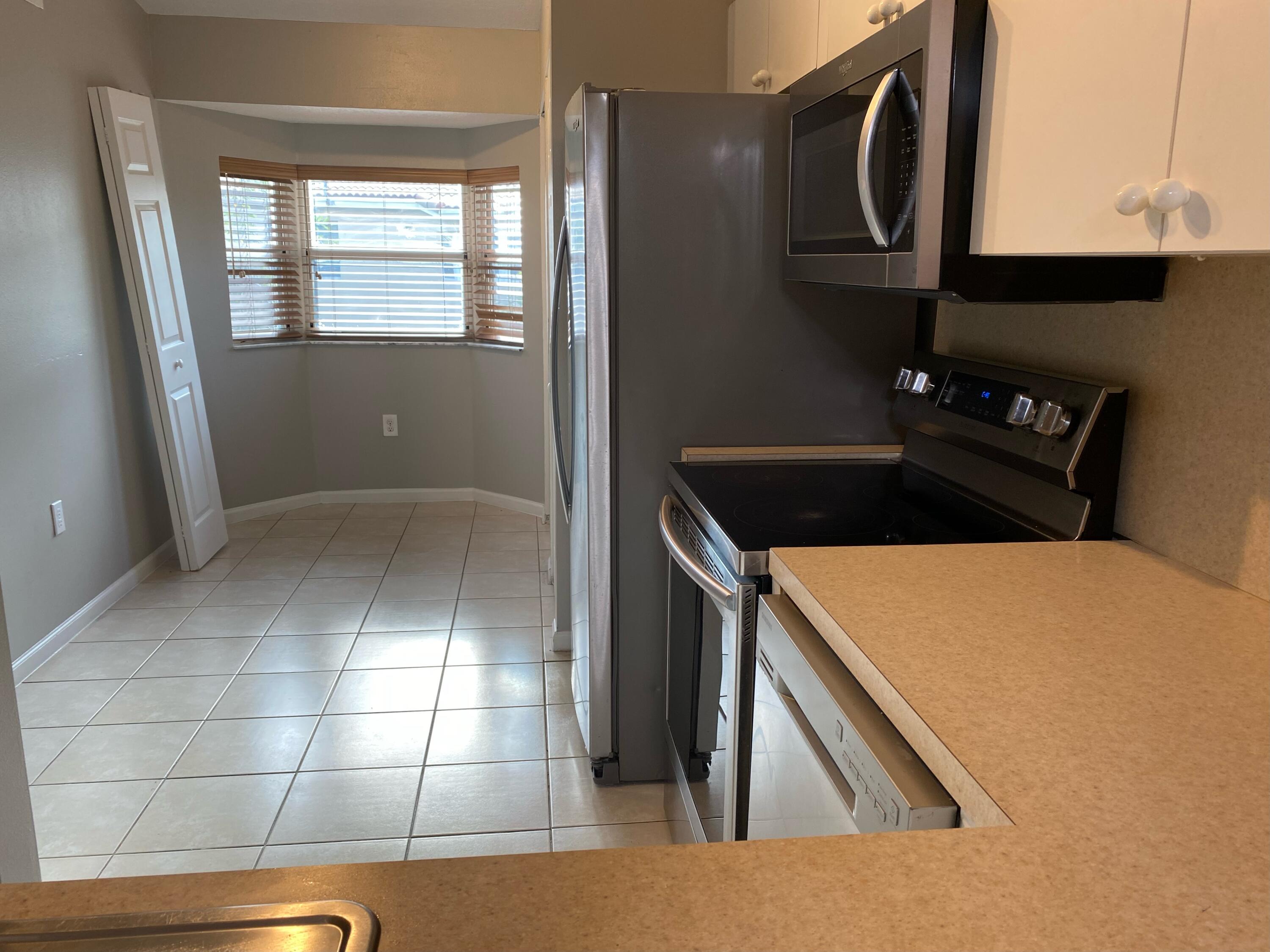 3501 Briar Bay Boulevard, Unit 205 West Palm Beach, FL 33411 - Photo 5 of 8 a kitchen with a sink a stove and cabinets