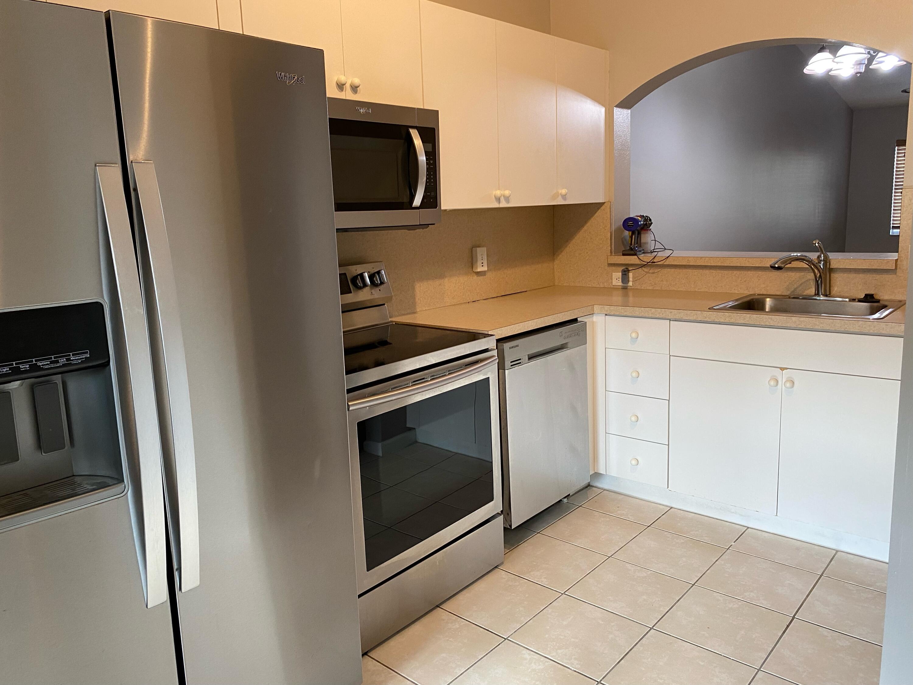 3501 Briar Bay Boulevard, Unit 205 West Palm Beach, FL 33411 - Photo 6 of 8 a kitchen with metallic refrigerator and a sink