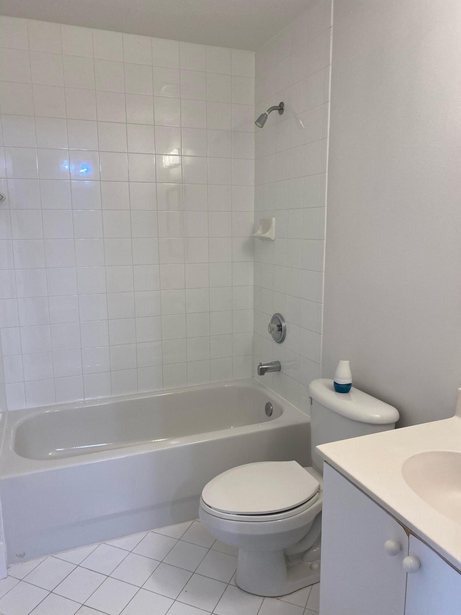 3501 Briar Bay Boulevard, Unit 205 West Palm Beach, FL 33411 - Photo 7 of 8 a white toilet and tub sitting next to a bathroom sink