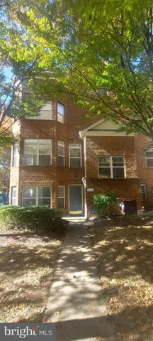 a view of a brick house next to a yard with large trees