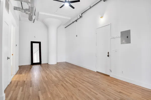 a view of an empty room with wooden floor and closet
