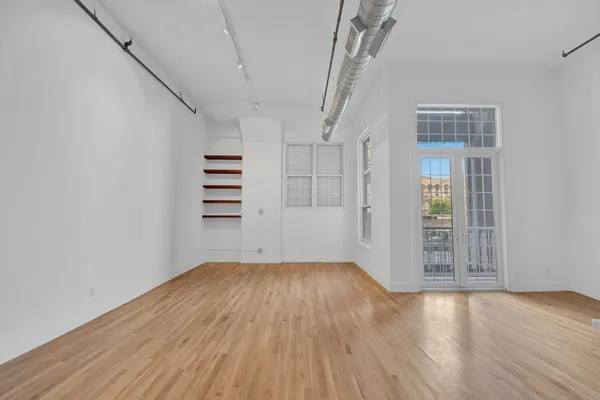 a view of a big room with wooden floor and windows