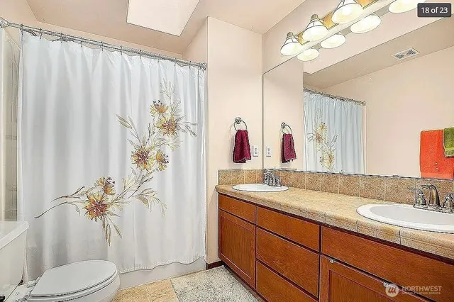 a bathroom with a granite countertop sink a toilet and a mirror