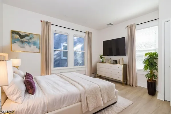 a bedroom with a bed and a flat tv screen on dresser