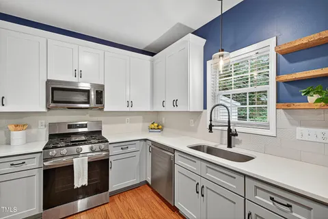 a kitchen with granite countertop a sink cabinets stainless steel appliances and a window