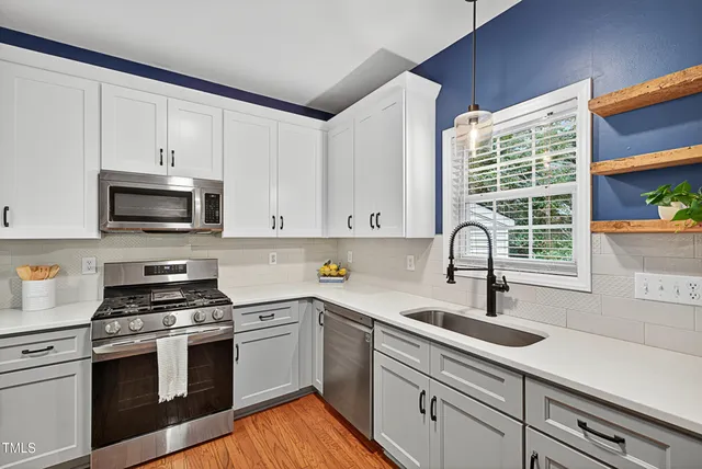 a kitchen with granite countertop a sink cabinets stainless steel appliances and a window