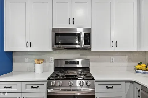 a kitchen with stainless steel appliances granite countertop white cabinets and a stove a oven with white countertops