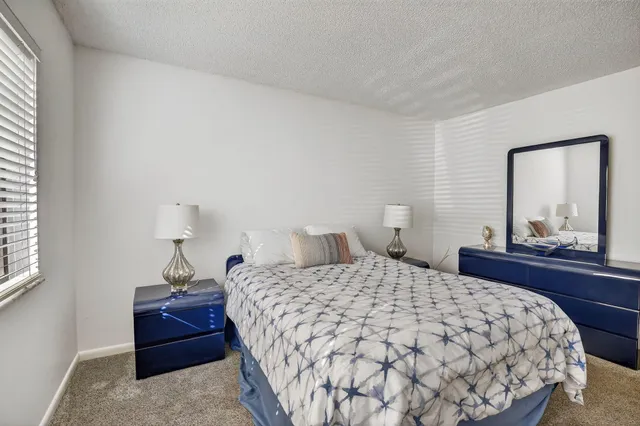 a bedroom with a bed and a lamp on dresser