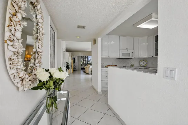a white kitchen with stainless steel appliances a white table chairs