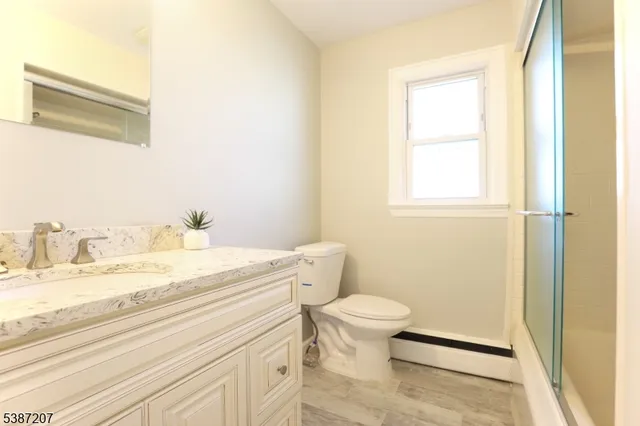 a bathroom with a granite countertop sink toilet and a mirror