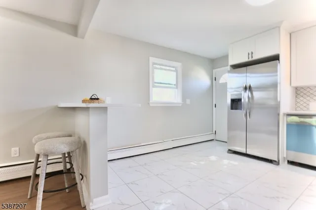a view of a refrigerator in kitchen and an empty room