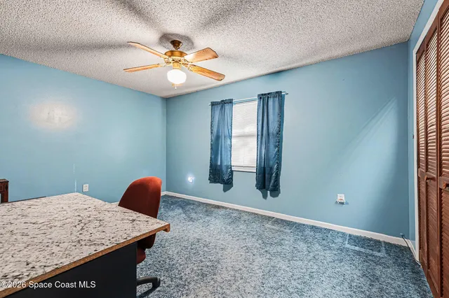 a view of a livingroom with a chandelier fan and a window
