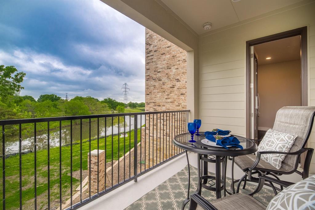 770 North Plano Road, Unit 303 Richardson, TX 75081 - Photo 21 of 26 The property features a balcony with a wrought iron railing, offering a scenic view of a body of water and lush green foliage