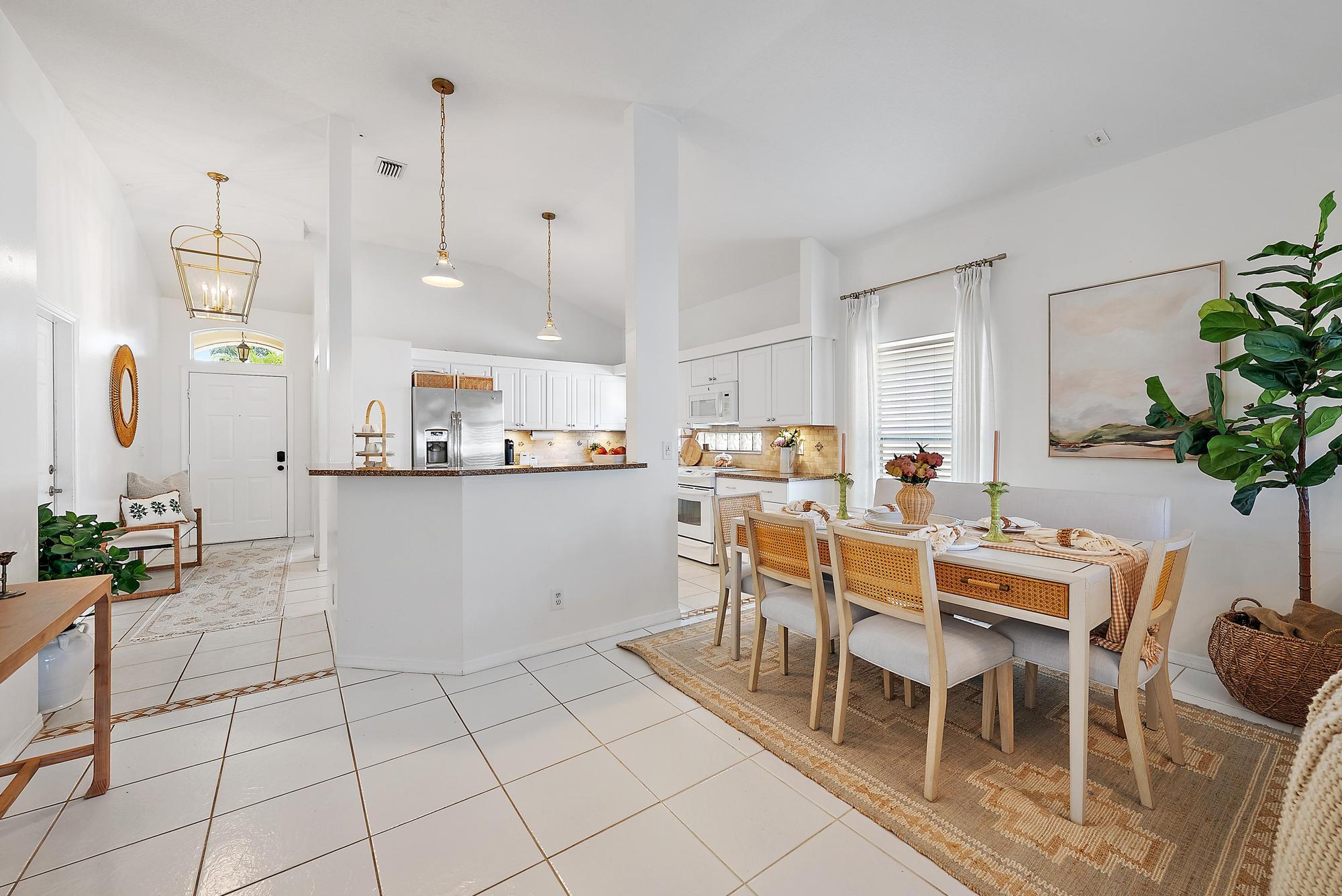 5010 Elpine Way Riviera Beach, FL 33418 - Photo 8 of 27 a kitchen with a dining table chairs and white cabinets