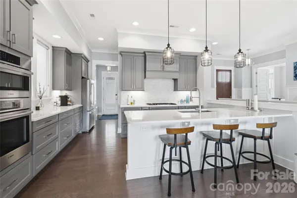 a kitchen with stainless steel appliances kitchen island granite countertop a table chairs sink and cabinets