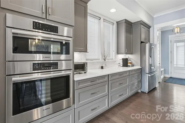 a kitchen with stainless steel appliances white cabinets and wooden floors