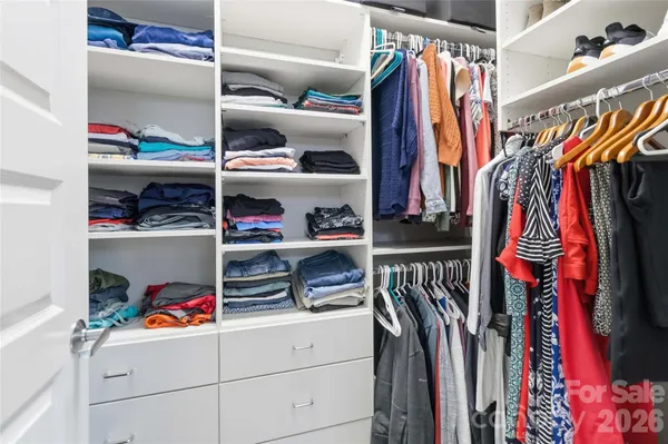 a view of walk in closet with clothes and shoes