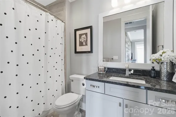 a bathroom with a granite countertop sink mirror vanity and toilet