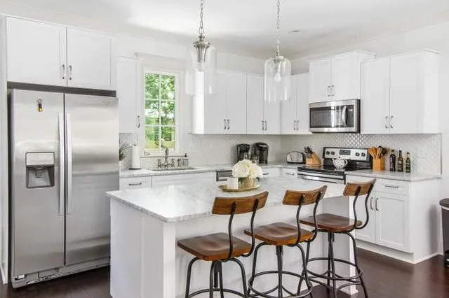 a kitchen with stainless steel appliances granite countertop a refrigerator a sink a stove a dining table and chairs