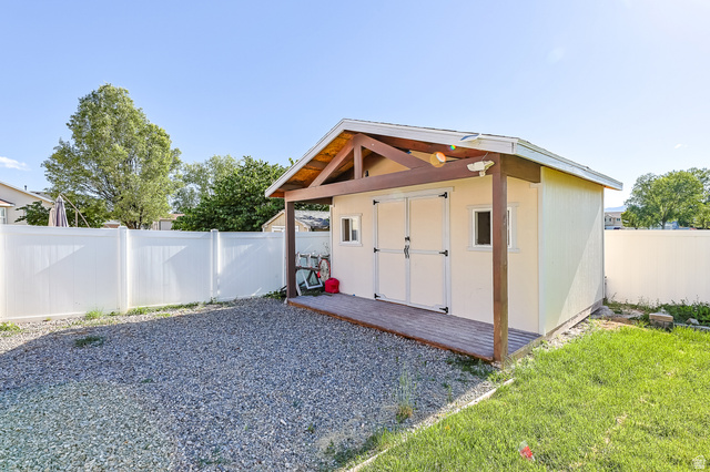 5525 Hampton Way Stansbury Park, UT 84074 - Photo 33 of 35 Detached shed featuring a covered wood-finish deck, double entry doors, two windows, and a vinyl fence