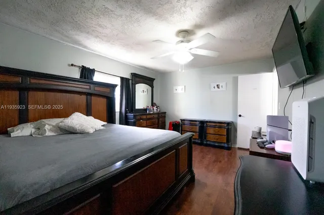 a bedroom with a bed and a flat tv screen on dresser