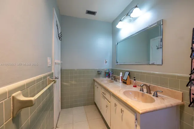 a bathroom with a double vanity sink a mirror and a bathtub