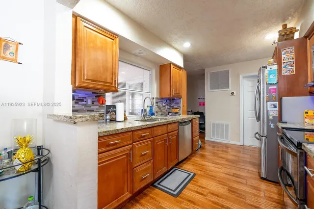 a kitchen with stainless steel appliances granite countertop a sink cabinets and wooden floor