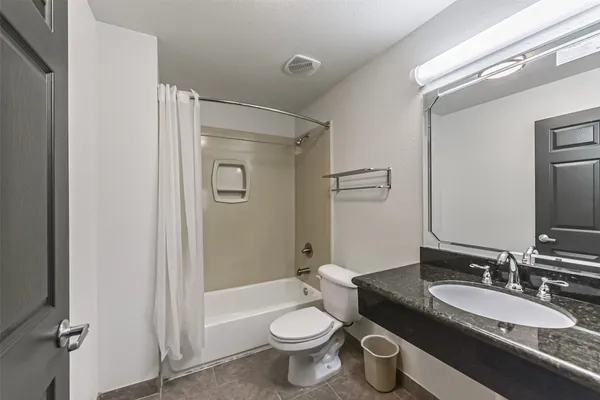 a bathroom with a granite countertop toilet a sink and a mirror