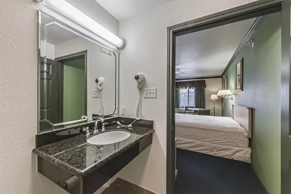 a en suite bathroom with a granite countertop sink and a mirror