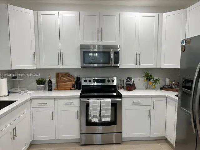 a kitchen with granite countertop white cabinets and white appliances