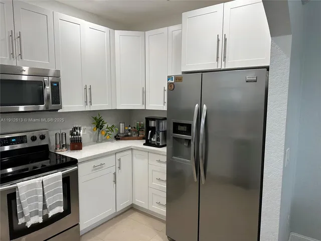 a kitchen with a refrigerator sink and white cabinets