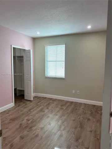 a view of an empty room with wooden floor and closet