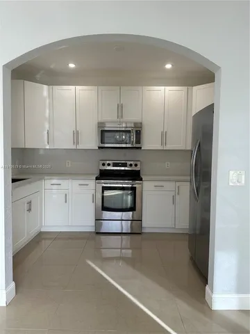 a kitchen with stainless steel appliances white cabinets and a refrigerator