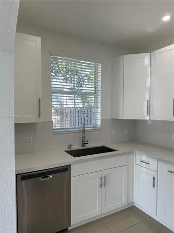 a kitchen with white cabinets and a window