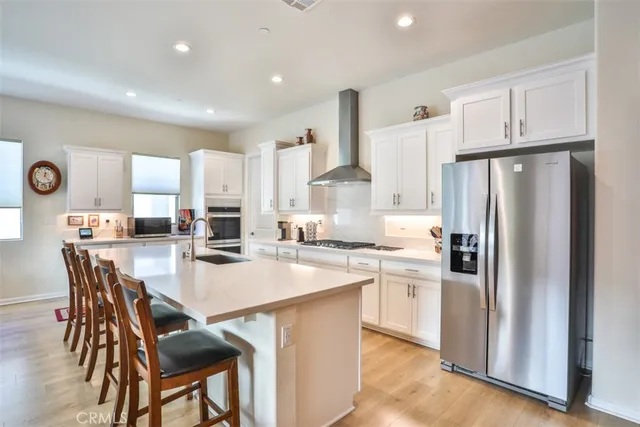 a kitchen with stainless steel appliances a refrigerator a stove a sink a table and chairs