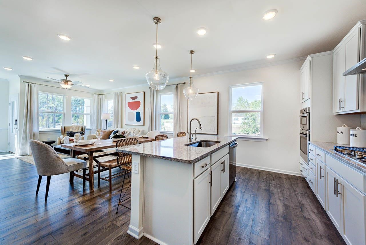 1714 Wimberly Road Apex, NC 27523 - Photo 11 of 45 a kitchen with stainless steel appliances granite countertop a stove a sink dishwasher and a dining table with wooden floor
