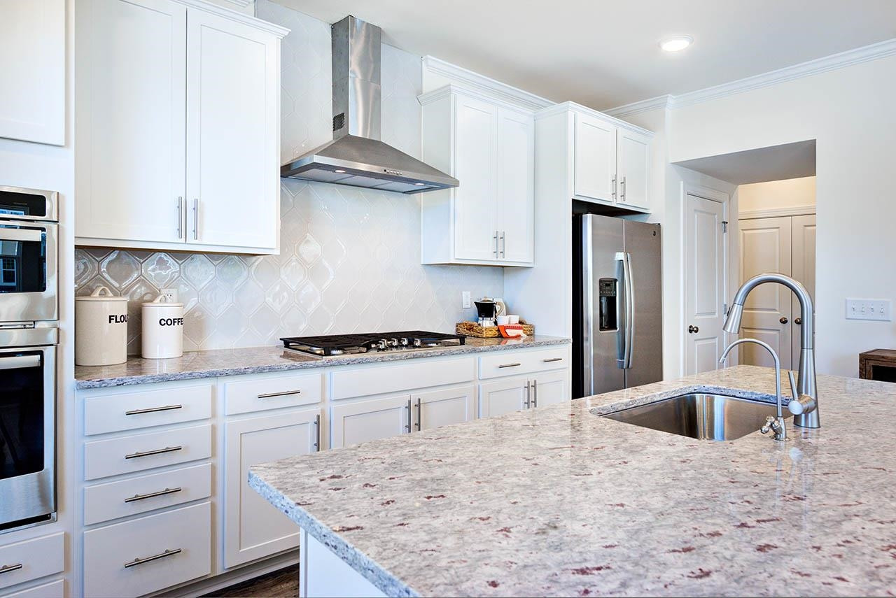 1714 Wimberly Road Apex, NC 27523 - Photo 12 of 45 a kitchen with stainless steel appliances granite countertop a sink stove and refrigerator