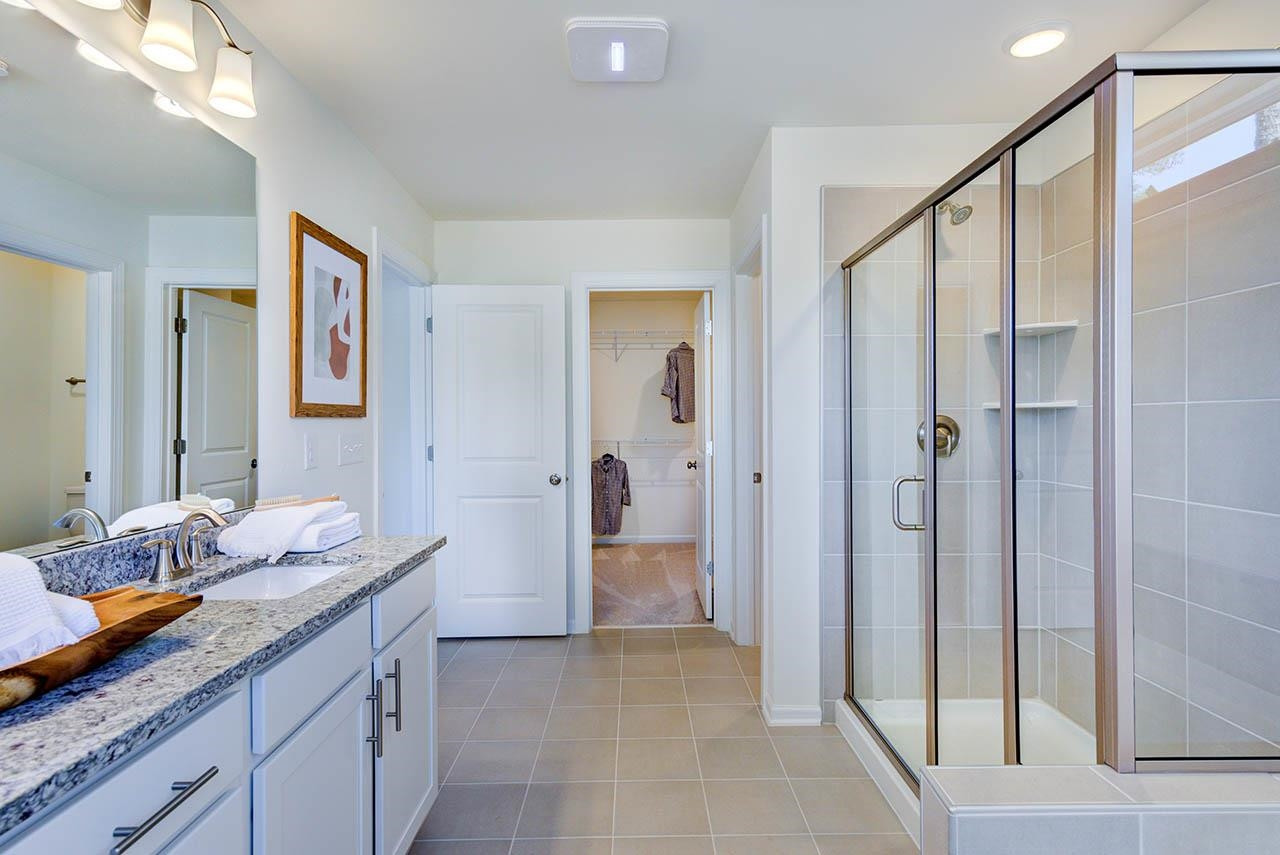 1714 Wimberly Road Apex, NC 27523 - Photo 25 of 45 a bathroom with a granite countertop sink mirror and shower