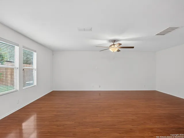 a view of empty room with wooden floor and fan