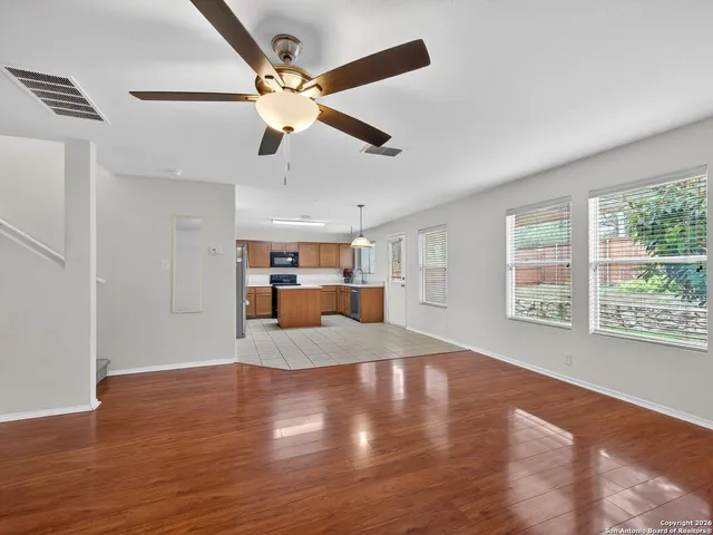 a view of empty room with wooden floor and fan