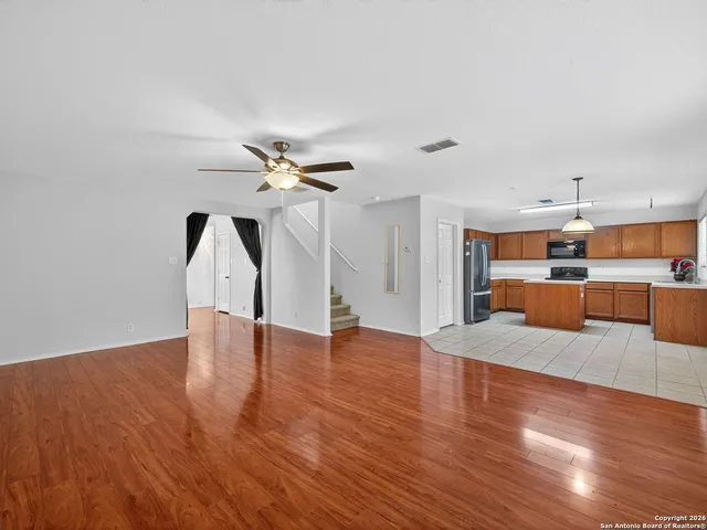 a view of empty room with wooden floor and ceiling fan