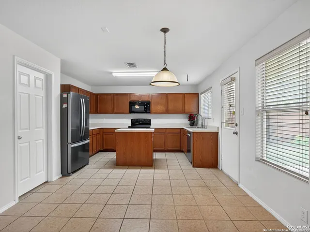 a kitchen with stainless steel appliances kitchen island granite countertop a refrigerator a sink a stove and white cabinets