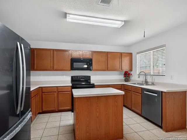 a kitchen with stainless steel appliances a sink stove refrigerator and cabinets
