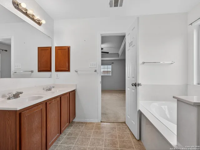 a bathroom with a tub sink and mirror