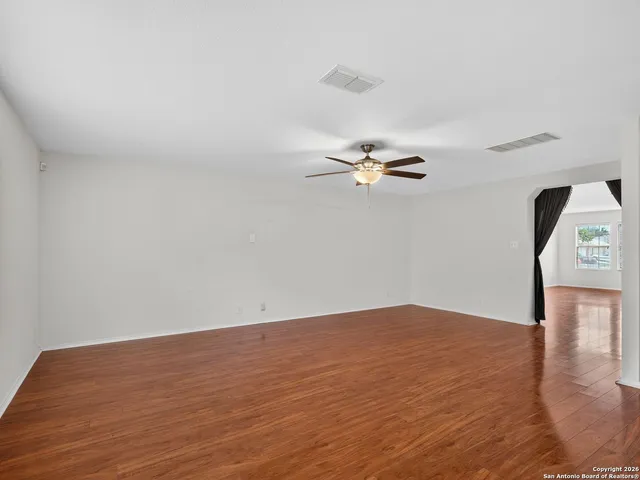 a view of a room with wooden floor and ceiling fan