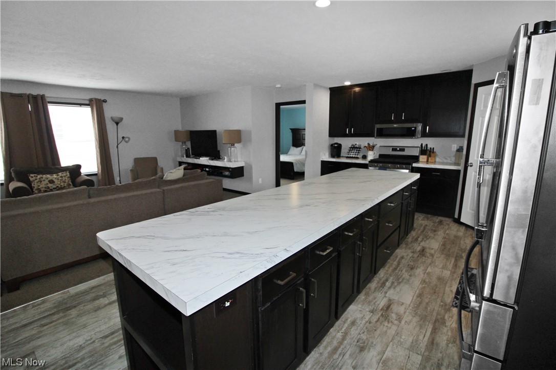 1609 Coldwater Crossing Road Lakeside Marblehead, OH 43440 - Photo 23 of 38 Kitchen featuring hardwood / wood-style floors, appliances with stainless steel finishes, light stone countertops, and a center island