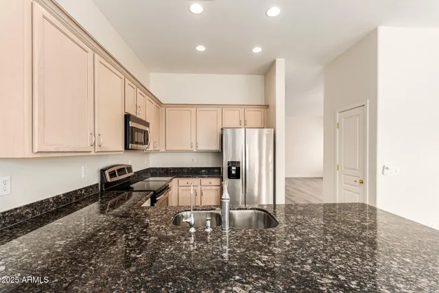 a kitchen with stainless steel appliances granite countertop a refrigerator a stove a sink and white cabinets with wooden floor